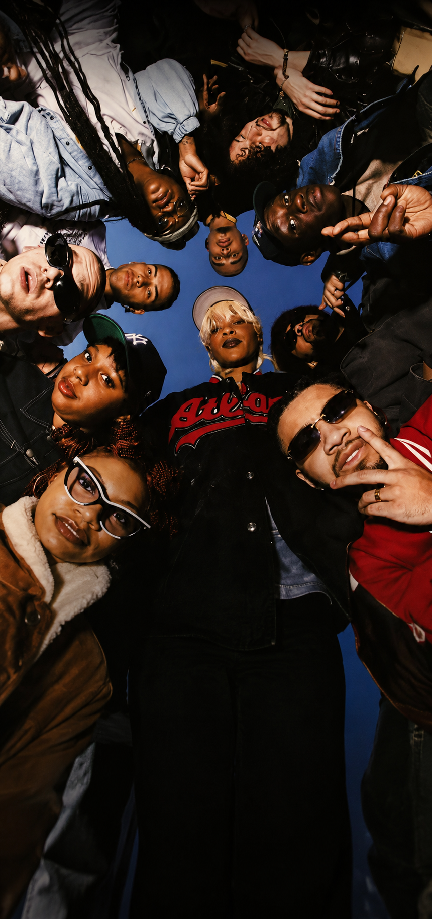 Group of people looking down at the camera in a circle against a blue sky